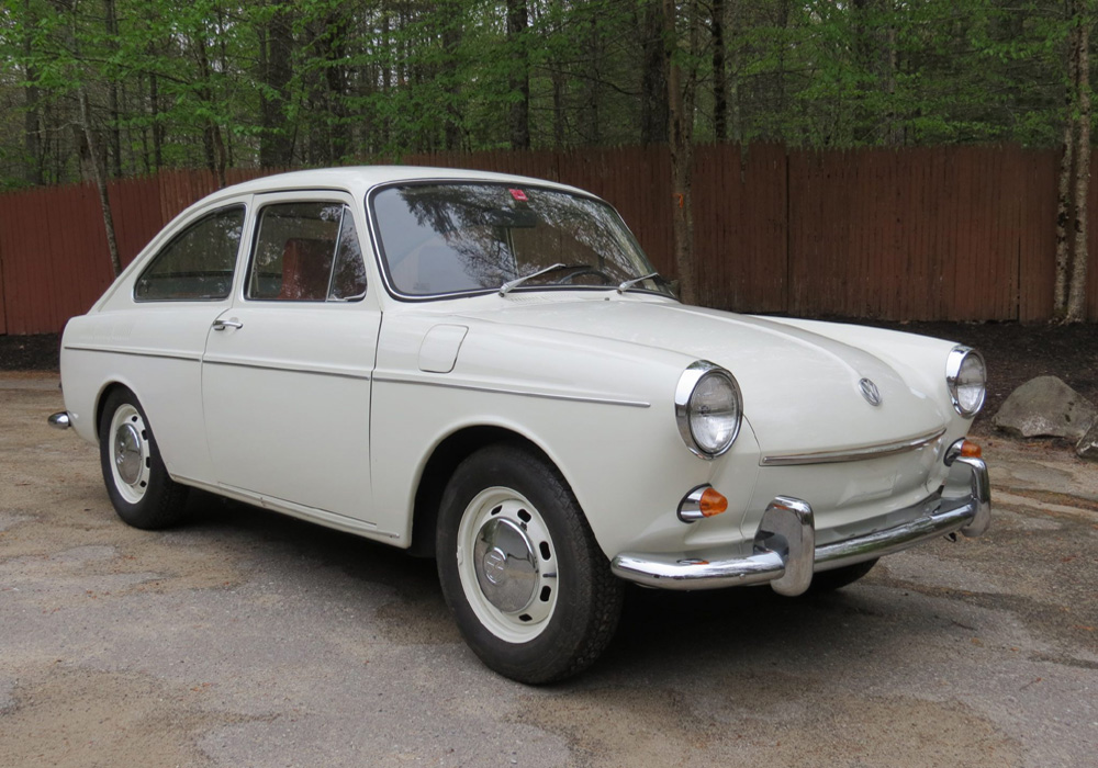 Classic Volkswagen Type 3 driving on a cobblestone street in a busy European town